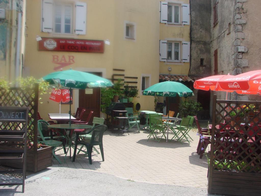 an outdoor patio with tables and chairs and umbrellas at Le Coq en Pâte in La Roque-Esclapon