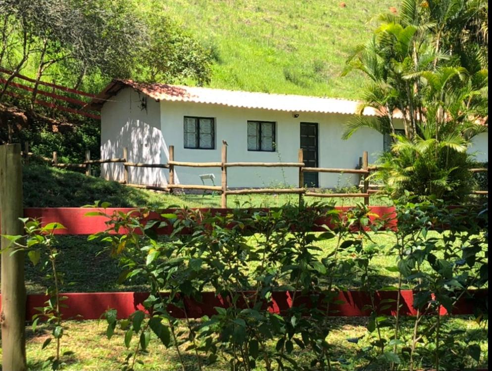 Uma casa branca com uma cerca vermelha à frente. em Vivenda dos Guaranys -Uma imersão na natureza - Casa em Conservatória