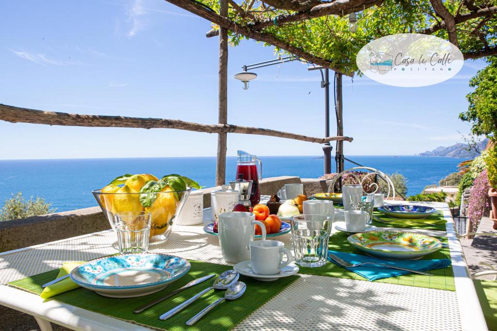 a table with plates of food on a table with the ocean at Casa Le Calle in Positano