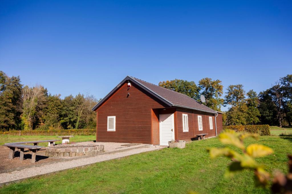 un granero rojo con una mesa de picnic y un banco en Gitstapper Hof natuurhuis, en Wassenberg