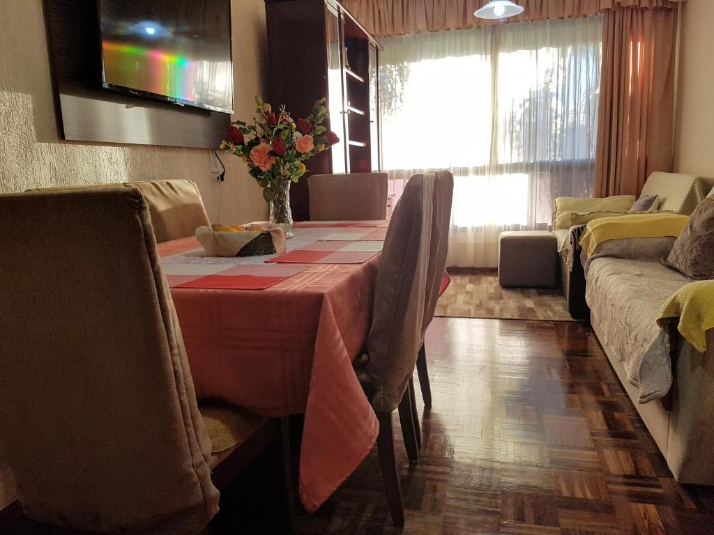 a dining room with a table with chairs and a television at Apartamento Aconchegante e Confortável com ou sem Ar Condicionado in Porto Alegre