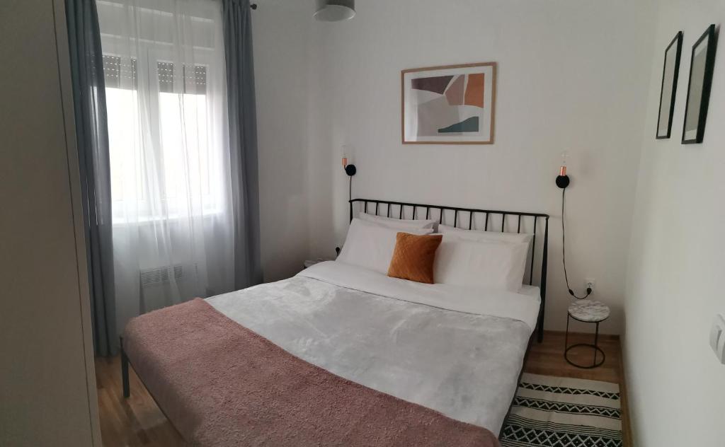a bed with white sheets and orange pillows in a bedroom at Apartman Kardaš in Vrnjačka Banja