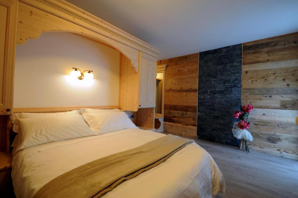 Un dormitorio con una cama grande y una pared con troncos. en Agritur Melissa, en Croviana