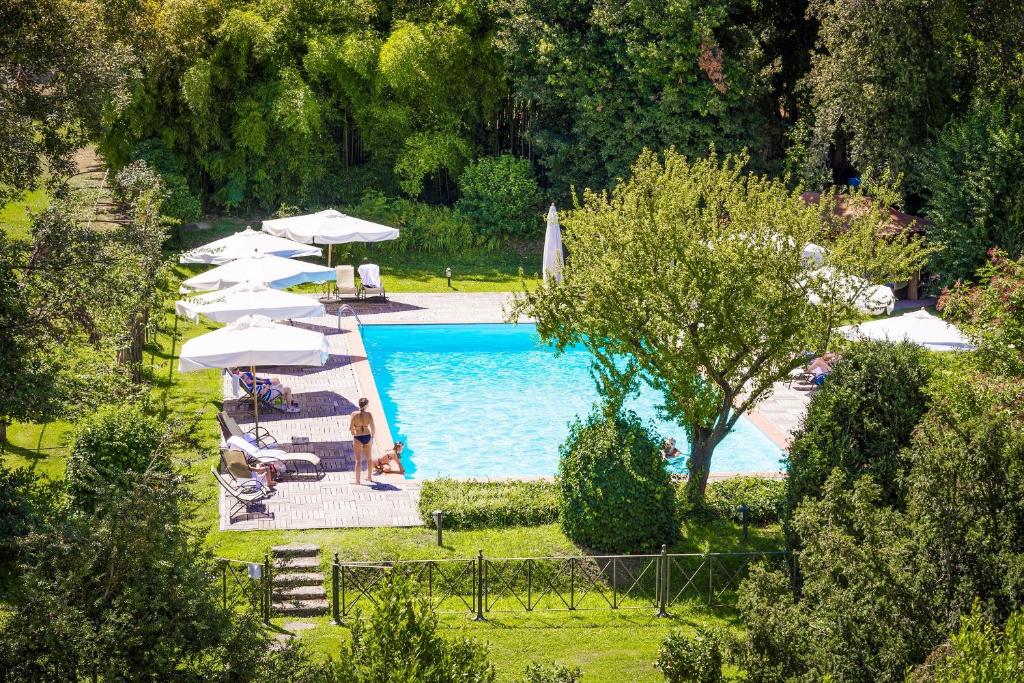 a swimming pool with umbrellas and a woman standing next to it at Hotel Villa La Principessa in Lucca