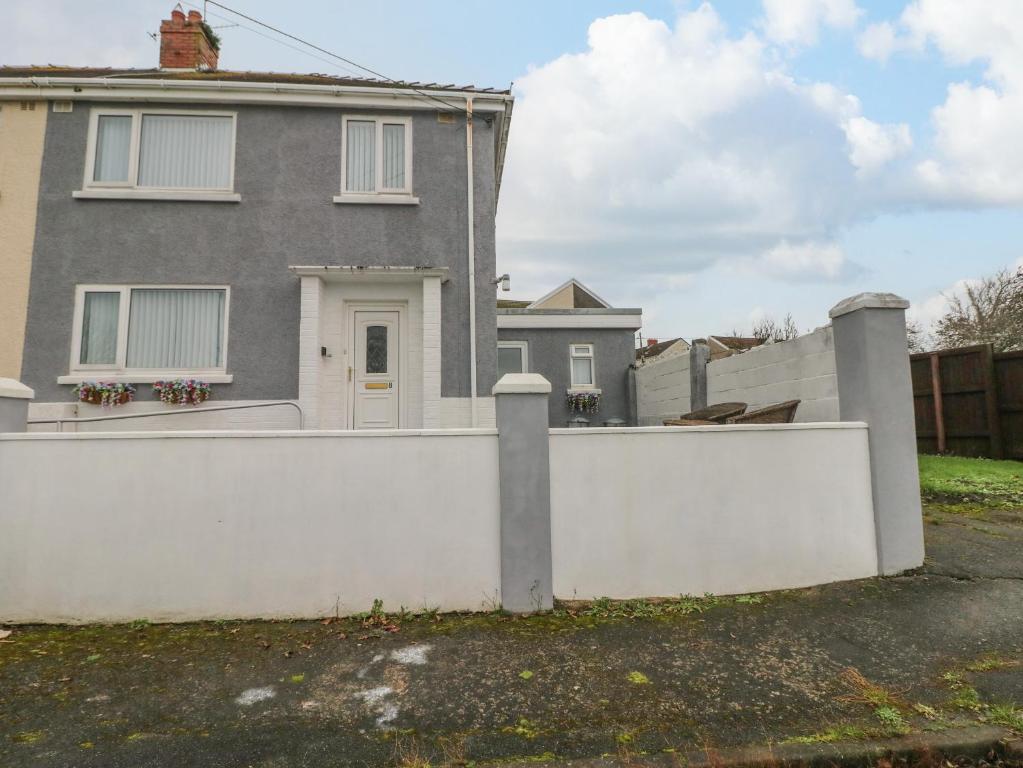 a white fence in front of a house at Cwtch Ar Y Mor in Burry Port