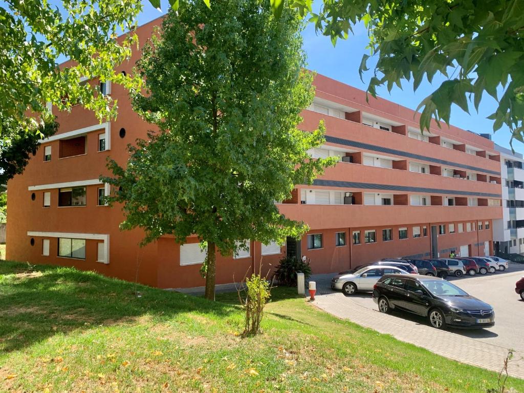 University of Minho- INL Campus Gualtar Apartment 2 في براغا: مبنى كبير به سيارات تقف في موقف للسيارات