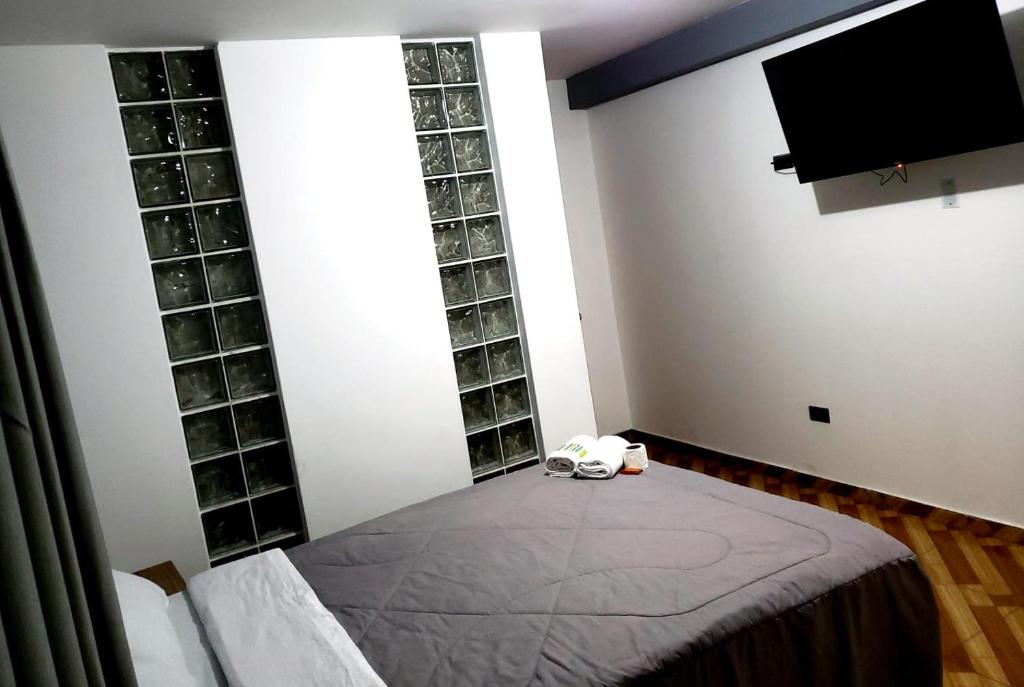 a bedroom with a bed and a flat screen tv at Tumalki Rooms in Trujillo
