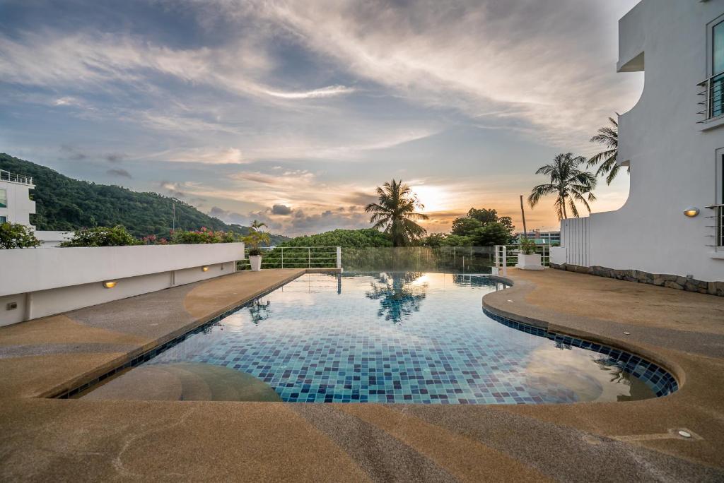 a swimming pool on the side of a building with the sunset at Kata Ocean View condominium by Lofty in Kata Beach