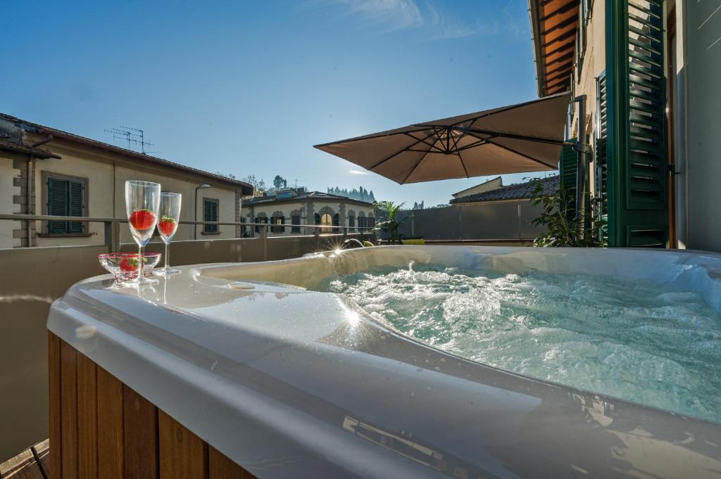 una vasca idromassaggio con 2 bicchieri di vino e un ombrello di CHIANTI LUXURY APARTMENTS GREVE a Greve in Chianti