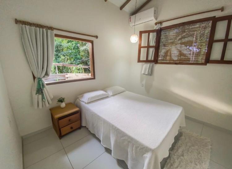 Un dormitorio con una cama blanca y una ventana. en Casinha no centro, en Trancoso