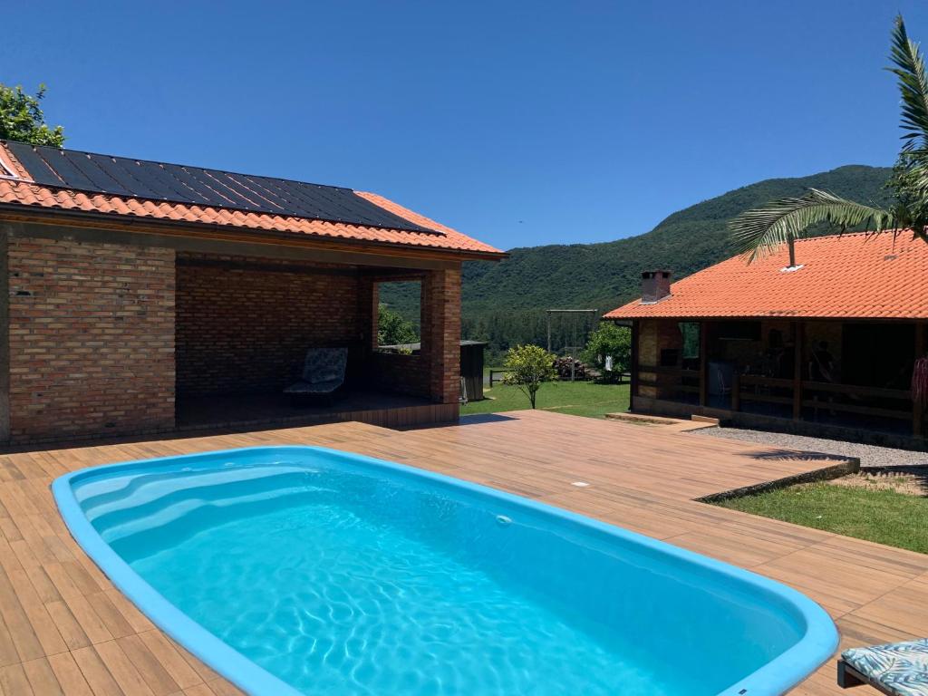 a blue swimming pool on a wooden deck next to a house at Costa Montana in Louro Müller