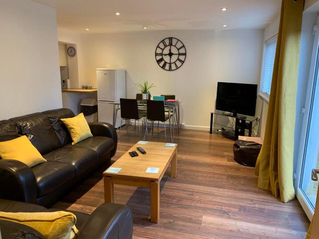 a living room with a leather couch and a coffee table at Bright House with Garden & Patio in Market Town in Inverurie
