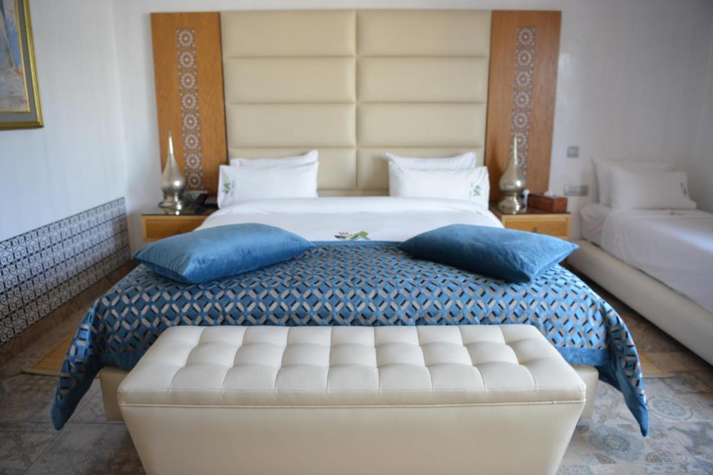 um quarto com uma cama king-size e almofadas azuis em Aralia Boutique Hôtel em Rabat