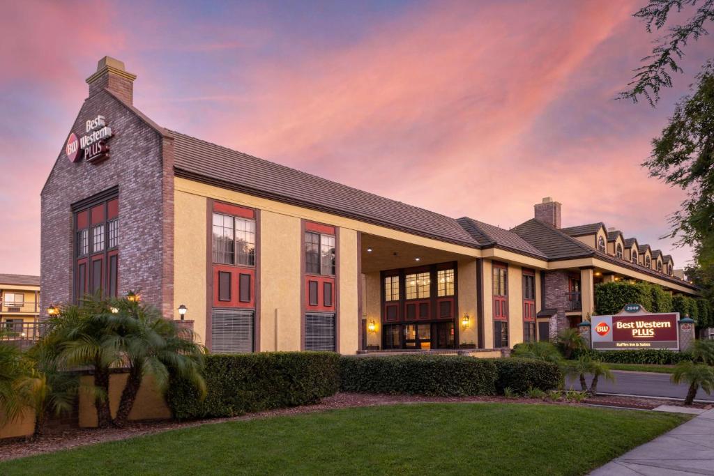 a large building with a sunset in the background at Best Western Plus Raffles Inn & Suites in Anaheim