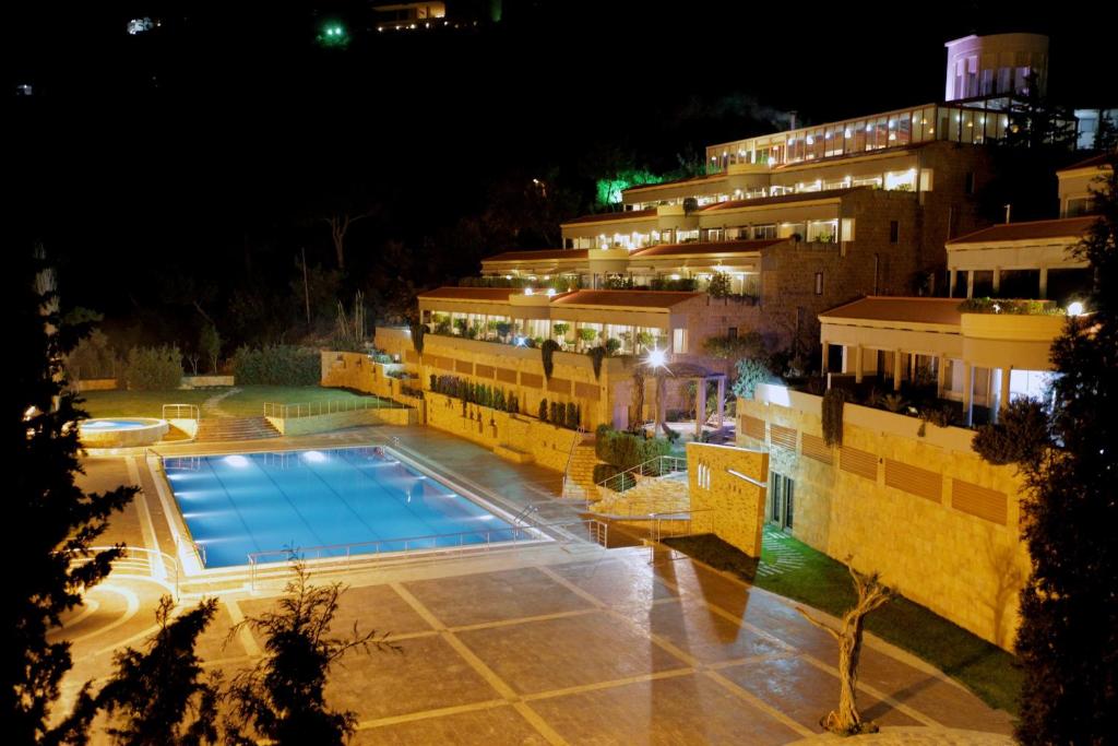 un hotel con piscina por la noche en Monteverde Hotel, en Beit Meri