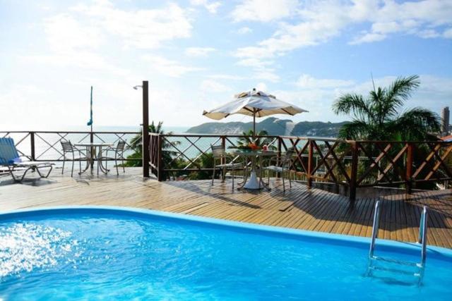 einen Pool mit einem Tisch und einem Sonnenschirm in der Unterkunft Marsallis Praia - Flat 404 - Vista Mar in Natal