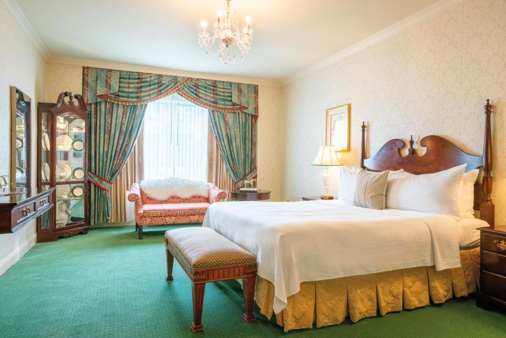 sypialnia z dużym białym łóżkiem i krzesłem w obiekcie The Bristol Hotel Campbell San Jose w mieście Campbell