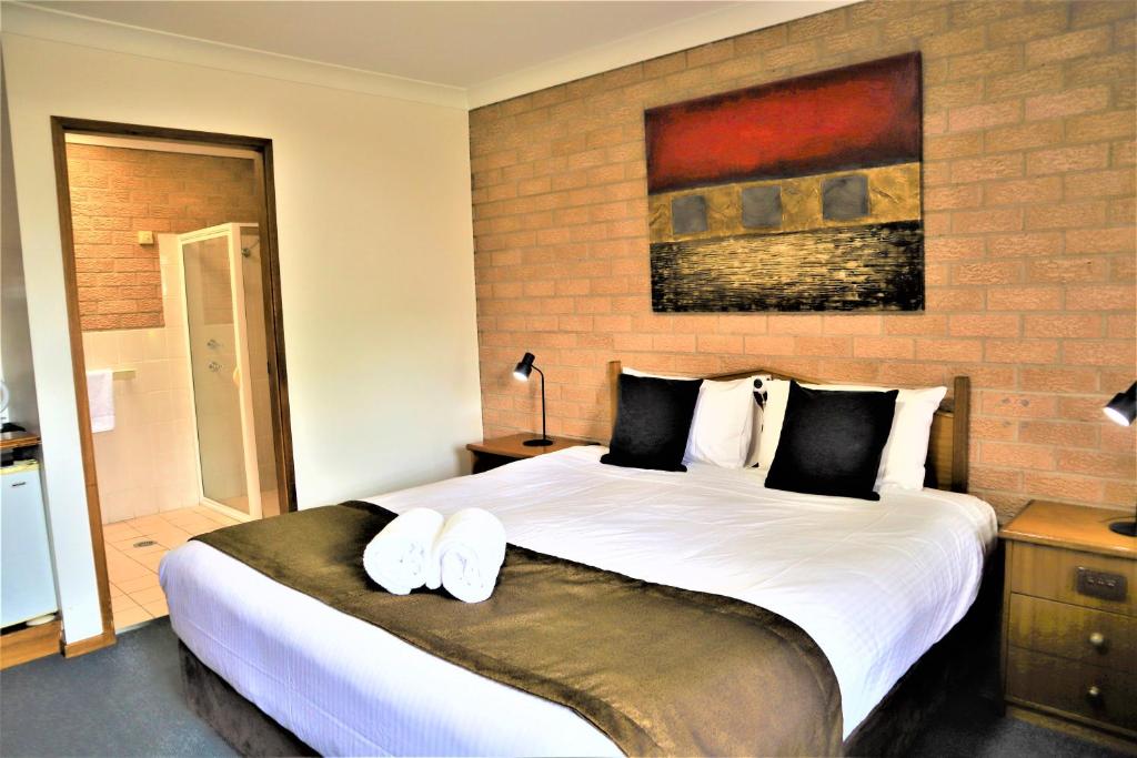 a bedroom with a large bed with two towels on it at Golden Chain Aalana Motor Inn in Cowra