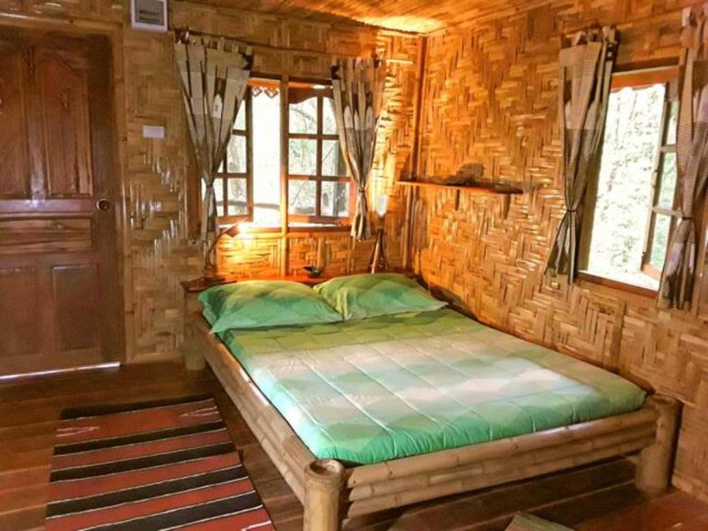 ein kleines Schlafzimmer mit einem Bett in einem Blockhaus in der Unterkunft Treehouse Holidays-Love Nest in Ko Yao Noi