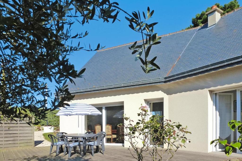 une maison blanche avec une table, des chaises et un parasol dans l'établissement Cottage, Hillion, à Hillion