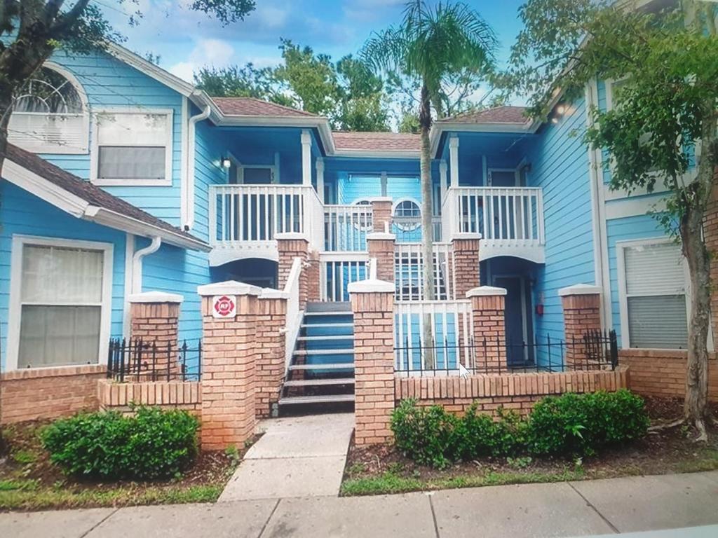 une maison bleue avec une clôture et des escaliers dans l'établissement Somerset Villas 84, à Kissimmee