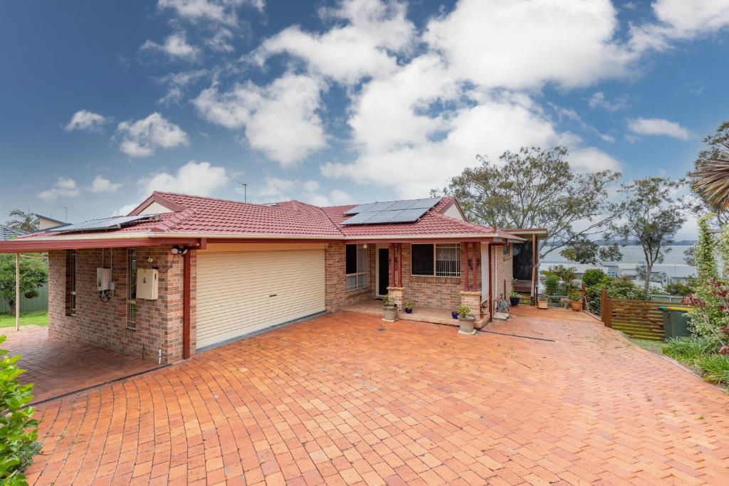 a house with a red roof on a brick driveway at Lakeview on Victoria in Forster