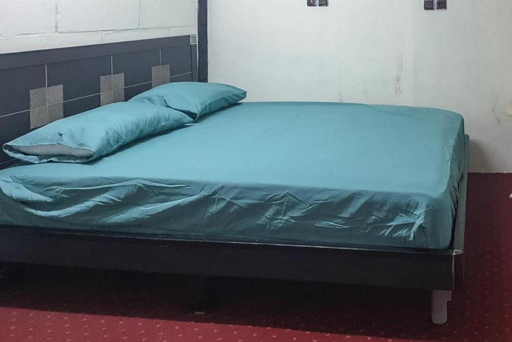 a bed with blue sheets and pillows in a room at Rocky Guest House Syariah Mitra RedDoorz in Sungai Lutus