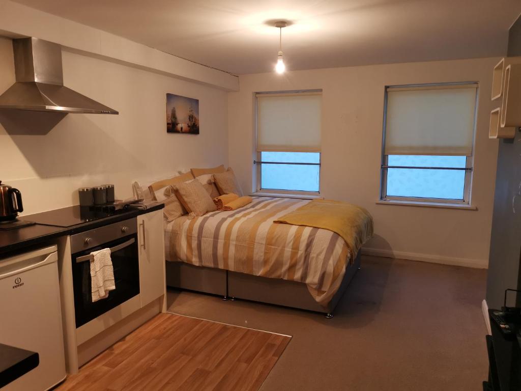 een kleine slaapkamer met een bed en een keuken bij Maidstone Heights II in Maidstone