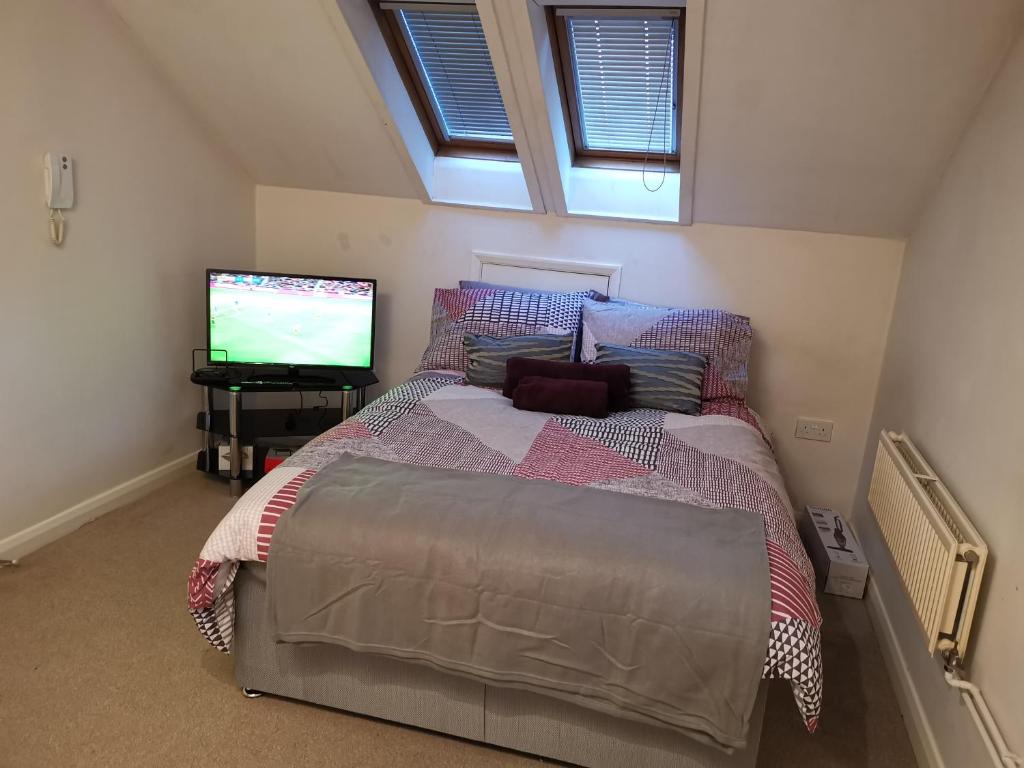 um quarto com uma cama e uma televisão em Unique Studio I - Private Studio with ensuite em Maidstone