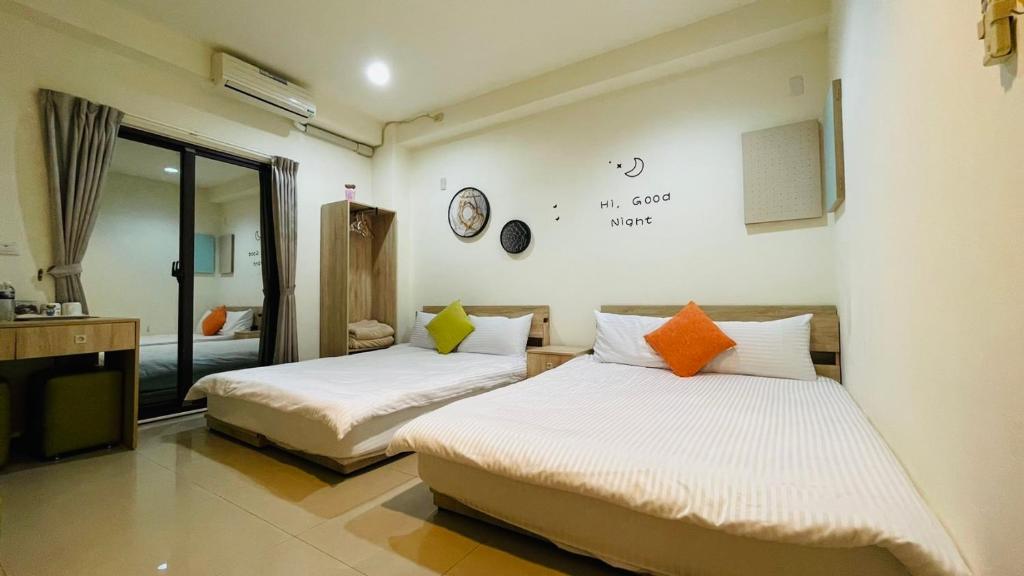 a bedroom with two beds and a clock on the wall at 八八小屋心享民宿 in Jinning