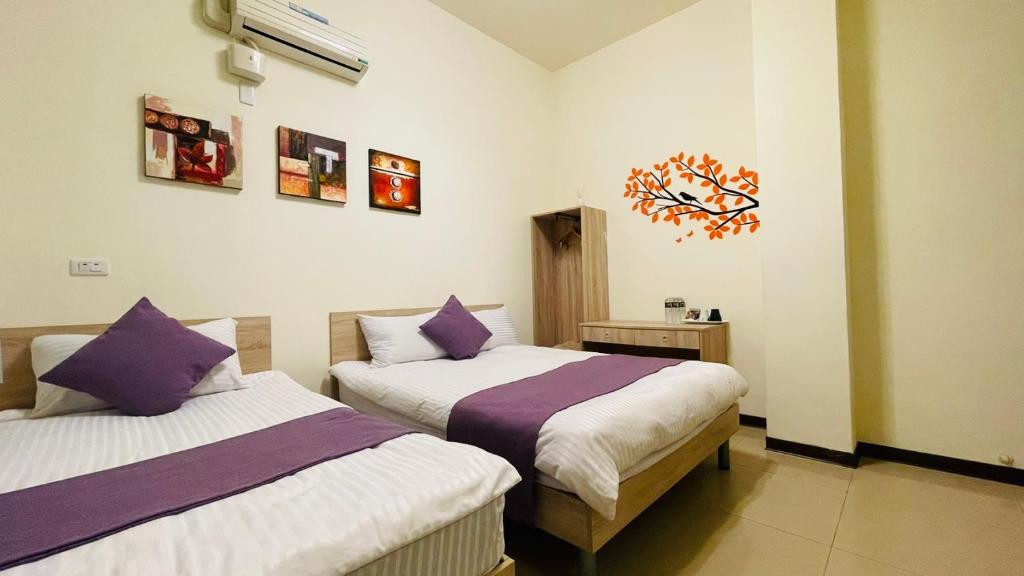 a bedroom with two beds with purple and white sheets at 八八小屋心享民宿 in Jinning