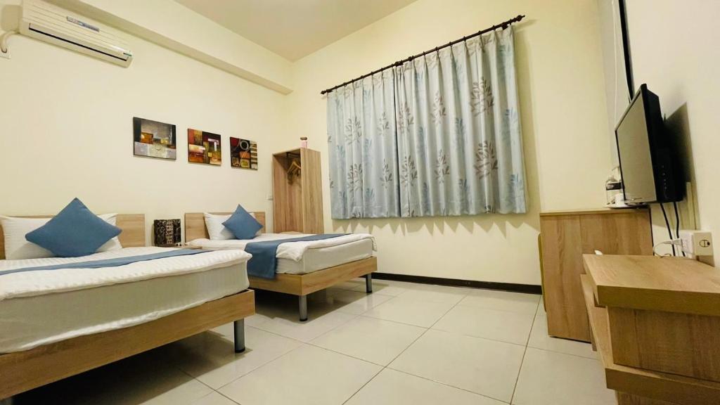 a room with two beds and a flat screen tv at 八八小屋心享民宿 in Jinning