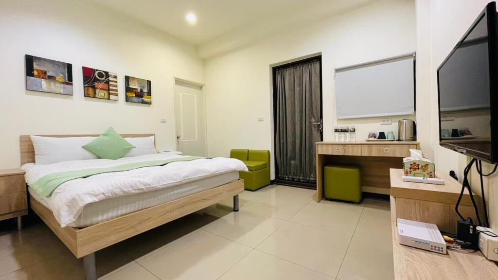 a bedroom with a bed and a desk and a television at 八八小屋心享民宿 in Jinning
