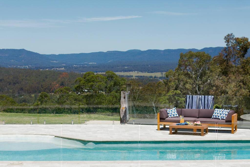 a couch sitting next to a swimming pool at The MOST alluring getaway in Hunter Valley in Mount View
