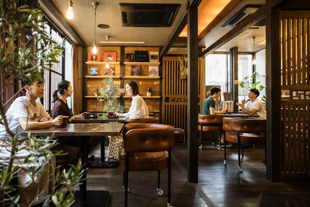 a group of people sitting at tables in a restaurant at Osaka Guest House U-En in Osaka