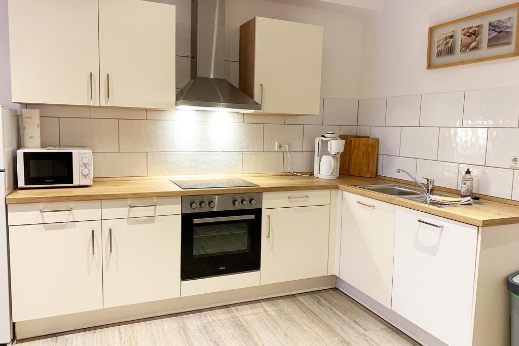 a kitchen with white cabinets and a stove top oven at Schöne Ferienwohnung bei Lennestadt in Kirchhundem