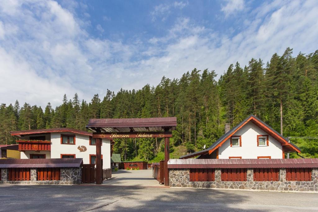 a building with a gate in front of a forest at Penzion Sabina in Vernár