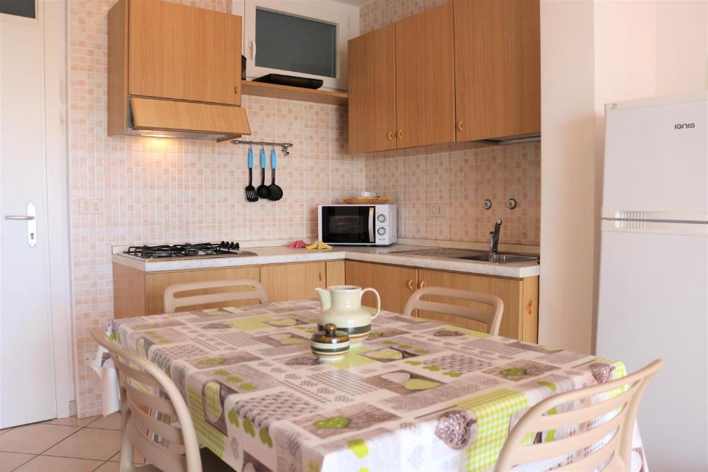 uma cozinha com uma mesa com cadeiras e um frigorífico branco em Beach front apartment with sea view - Beahost em Bibione