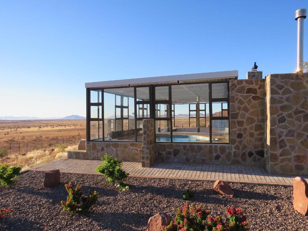 una casa de piedra con ventanas de cristal en una colina en Mountain View Villa en Maltahöhe