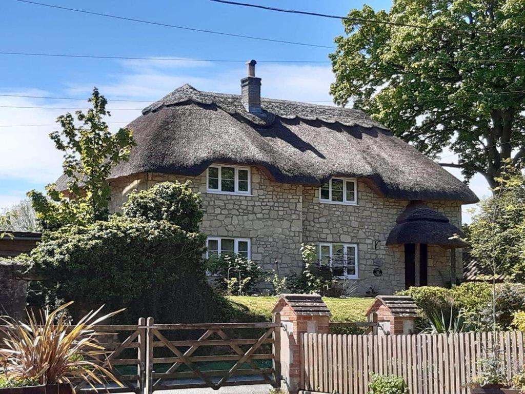 a large stone house with a thatched roof at Kings Cottage - Heart of the Deverills in Warminster