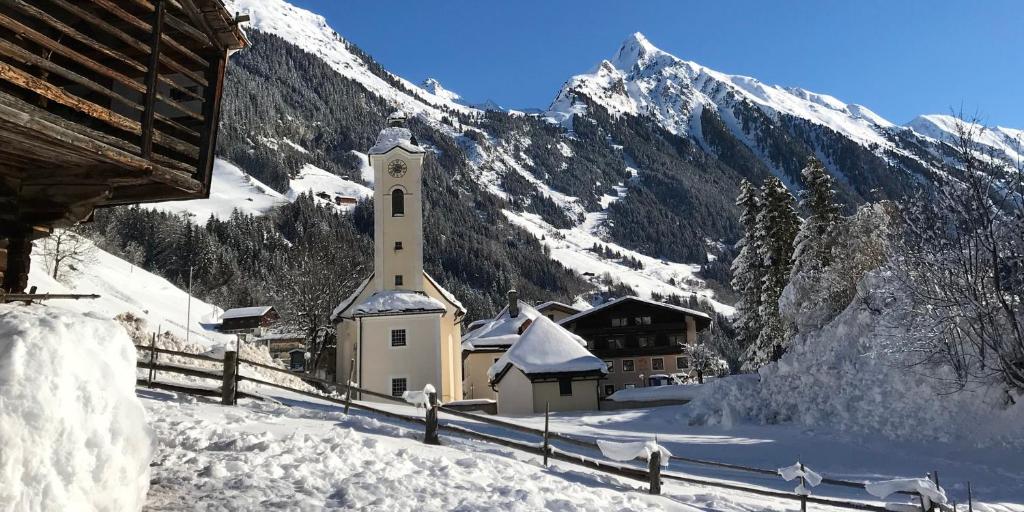 a church in the snow in front of a mountain at Haus Oblasser in Brandberg