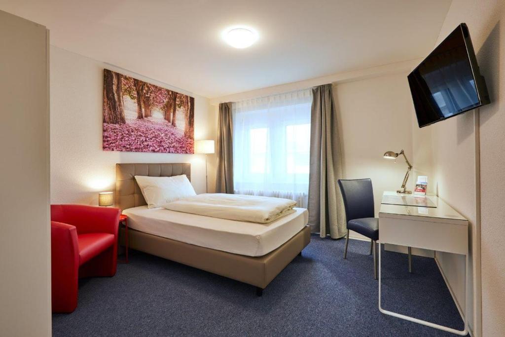 a hotel room with a bed and a red chair at Hotel Ambassador in Solothurn