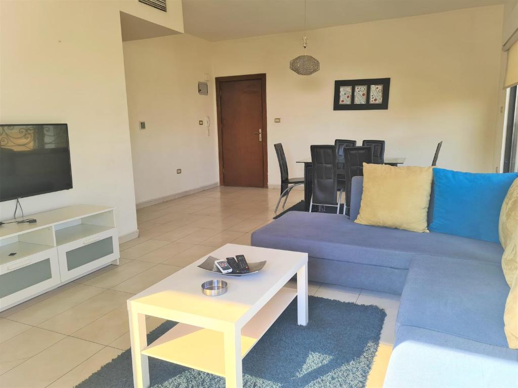 uma sala de estar com um sofá azul e uma mesa em Dair Ghbar Gate Apartments em Amã