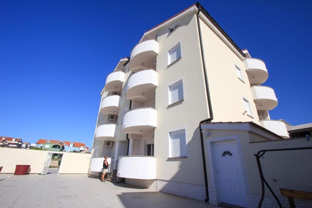 een persoon die voor een wit gebouw staat bij Apartments Dubrovnik Two in Povljana