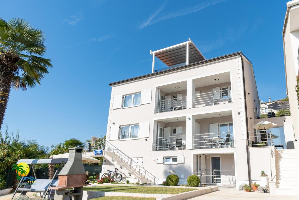 a white building with balconies and a palm tree at Villa Green Palm in Vrsar