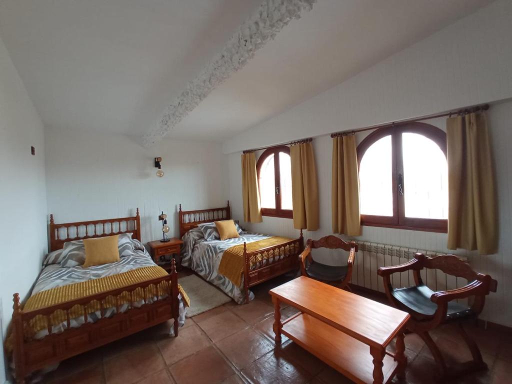 Un dormitorio con dos camas y una mesa y sillas. en CASA TURÍSTICA Villa Carmen, CON AMPLIO JARDIN QUE INCLUYE BARBACOA, 2 PORCHES, PARKING PRIVADO Y PISCINA, en Arenzana de Abajo