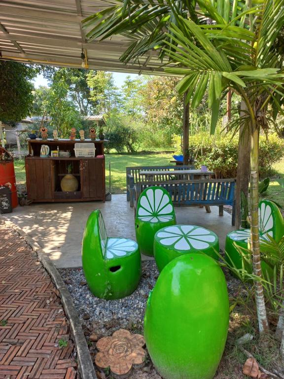 a patio with green chairs and a bench and a table at บ้านพักคุณยายเขียว in Ban Thung Kham