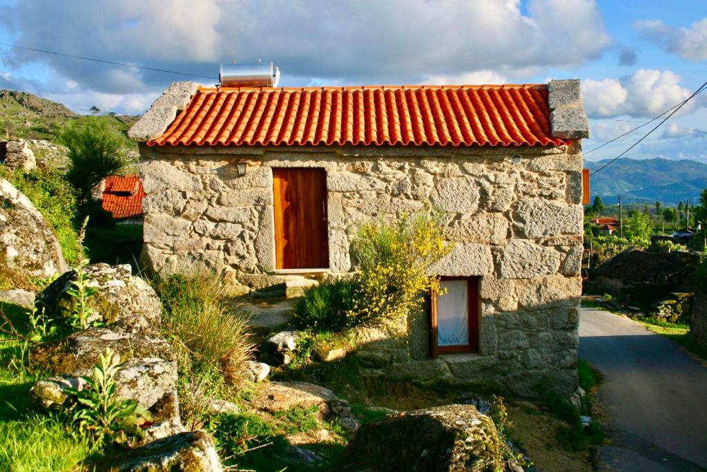 una pequeña casa de piedra con techo rojo en Casa do Castanheiro - Eido do Pomar, en Arcos de Valdevez