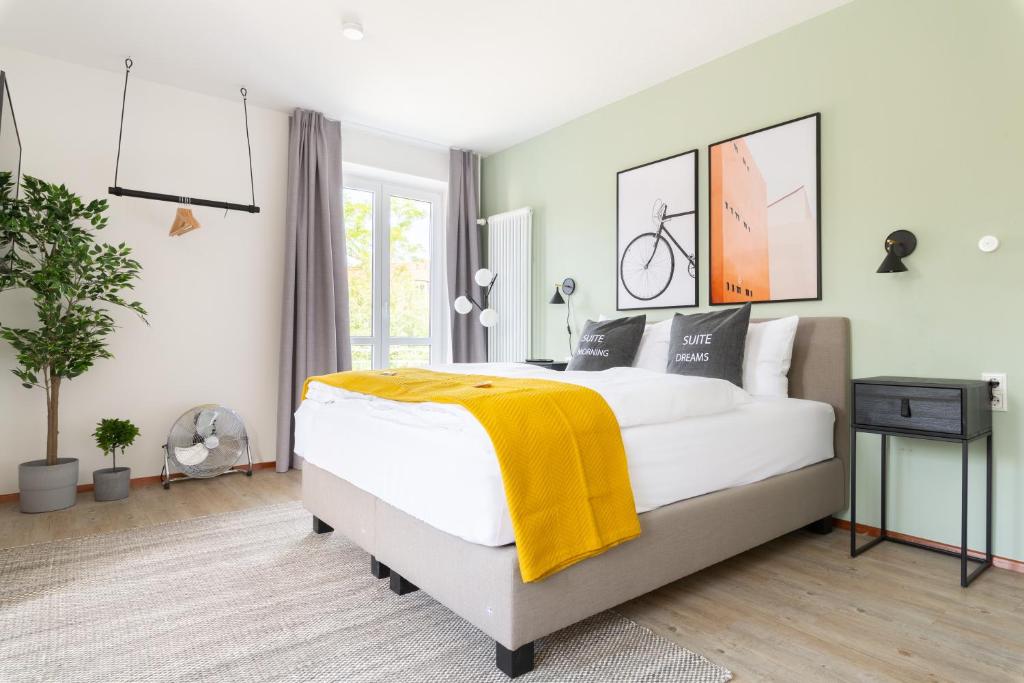 Un dormitorio con una cama con una manta amarilla. en limehome Garching bei München en Garching bei München