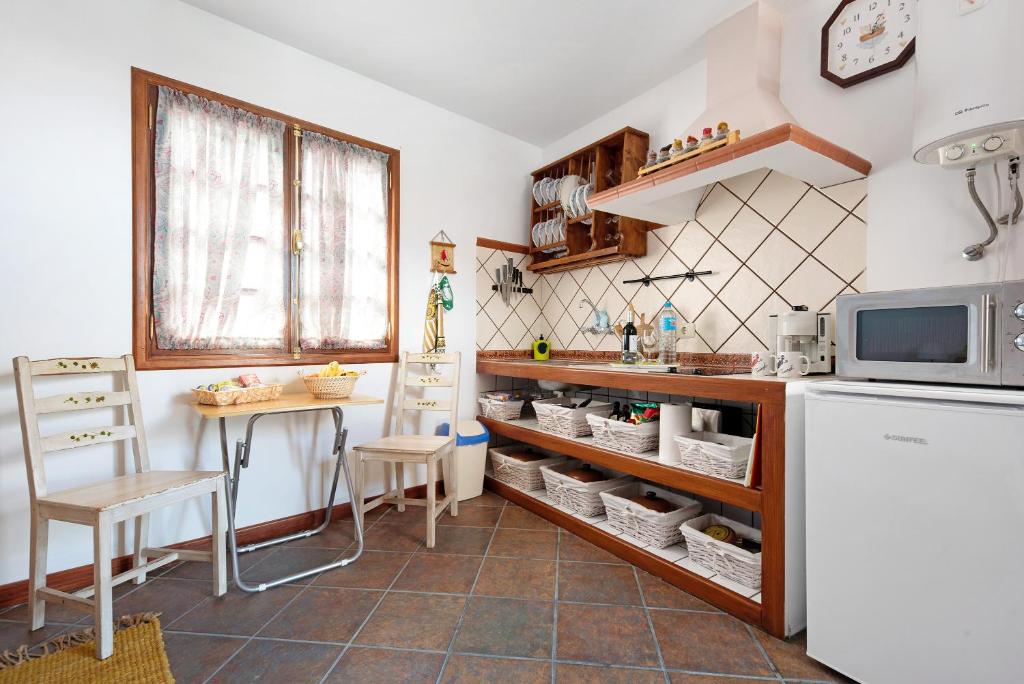 eine Küche mit einem Kühlschrank, einem Tisch und einer Mikrowelle in der Unterkunft La Casita Canaria in Los Silos